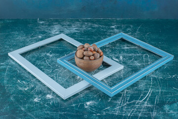 Two empty frames and a bowl of assorted nuts on blue background