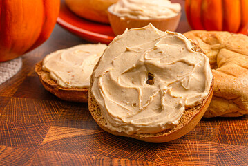 Pumpkin Bagel with Pumpkin Cream Cheese on a Wooden Table