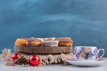 Dessert assortment with christmas baubles and a cup of tea on marble background