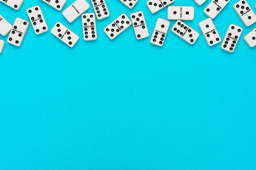 Domino pieces on turquoise blue background with copy space. Flat lay minimalist photo of some...