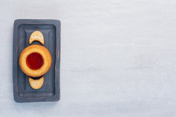 Crackers and a cake with jelly topping on a board on marble background