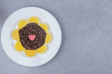 Pile of coffee beans and marmelades on a platter on marble background