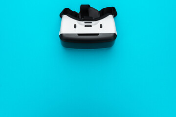 Virtual reality headset on turquoise blue background. Top view of VR helmet with copy space. Minimalist flat lay photo of white vr headset.