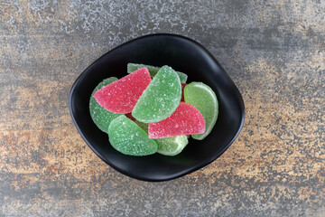 Small bowl full of marmelades on wooden background