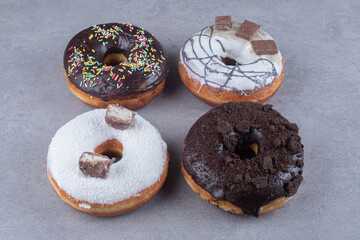 Four donuts with various toppings on marble background