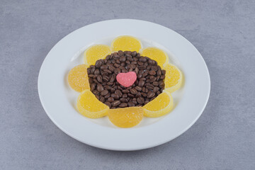 Coffee beans and marmelades on a platter on marble background