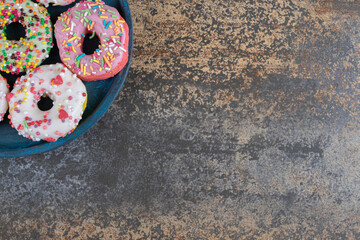 Blue platter with candy sprinkled donuts on wooden background