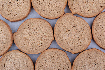 Three rows of black bread slices on marble background