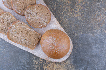 Brown bread slices bundled on a wooden board on marble background