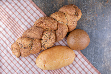 Assortment of bread loaves on a tablecloth on marble background