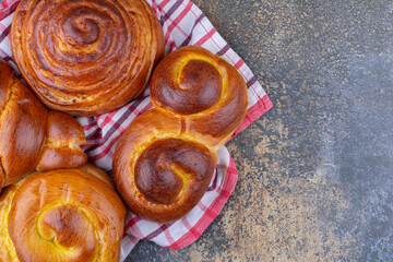 Delicious buns bundled up on a wrinkled towel on marble background