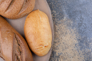 Assortment of bread types on a wooden board on marble background