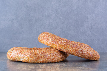Two sesame coated, crisp bagels on marble background