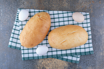 Buns and eggs displayed on a towel on marble background