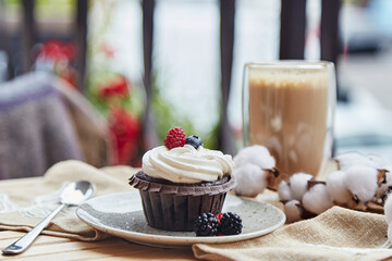 French gluten and sugar free raspberry and blueberry cupcake and cup of latte. Cozy autumn breakfast at the terrace.