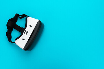 Virtual reality headset on turquoise blue background. Top view of VR helmet with copy space. Minimalist flat lay photo of white vr headset.