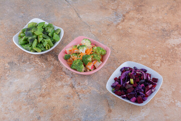 Freshly chopped vegetables mixed and bundled in bowls on marble background