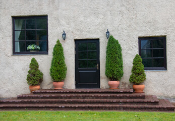 Porch with a black door, a large terrace, 4 arborvitae in a flower pot. A beautiful terrace of the...