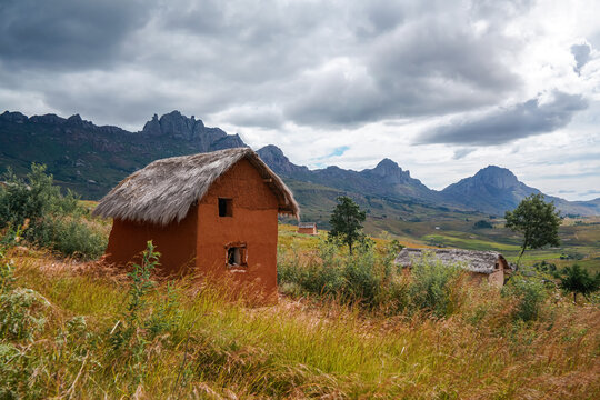 Typical landscape at Andringitra National Park, Madagascar on overcast day. Rocky mountains with rice fields under at distance, small clay house with stray roof in foreground © Lubo Ivanko