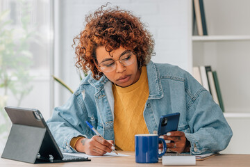 woman at home with laptop and mobile phone studying