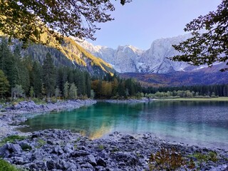 Fototapeta na wymiar Reflection of forest and mountains in Lake Superiore in Fusine in autumn at sunset on the Julian Alps, Italy