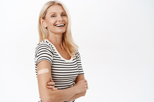 Happy And Healthy Mature Woman, 50 Years Old, Has Band Aid On Shoulder, Smiling And Laughing, Standing In Tshirt Over White Background