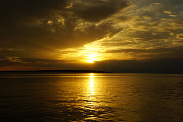 Fototapeta premium Dark heavy clouds on the sky and sun in the background at the beautiful golden seascape