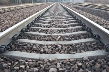 Deurstickers Railway lines with track ballast. Train tracks underlay, rails and crushed stones. Industrial landscape. Railway junction. Heavy industry. Railway track. © Piotr