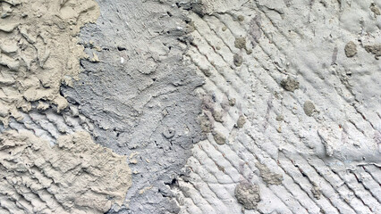 Uneven concrete surface of different colors. A concrete wall on which cement has been carelessly applied. The solution was applied at different times and has different shades of gray.