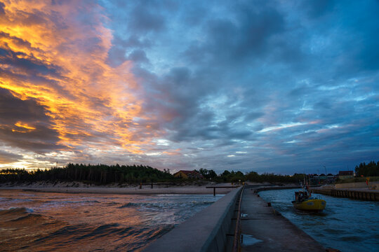 Fototapeta Wschód słońca w Rowach na Bałtykiem, rybacy wypływający w morze.