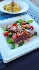 tagliata di tonno fresco servita in un piatto di carta con pomodorini e insalata