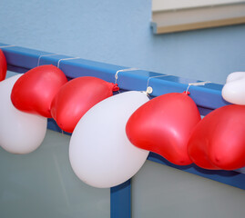 Luftballons in Herzform an einem Geländer befestigt zur Dekoration bei einer Hochzeit.