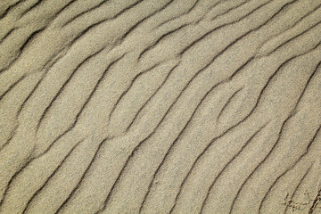 Eine durch Wind und Wellen entstandene Sandtextur am Strand.