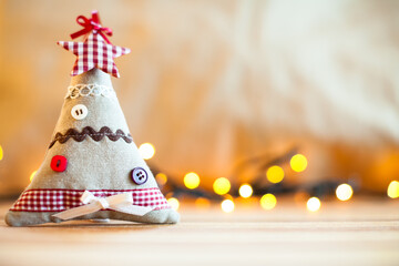 Small cloth christmas tree and blurred christmas lights in the background. Christmas decoration. - 534060017