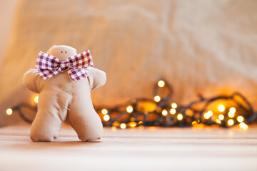 Handmade cloth gingerbread and blurred christmas lights in the background. Christmas decoration.