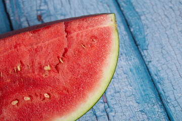 Fototapeta na wymiar Detail of a slice of a fresh red watermelon on a blue background