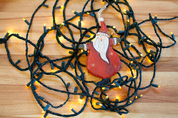Hand painted wooden Santa Claus leaning on Christmas lights
