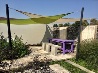 Lounge area in summer garden. Appeltern is the Netherlands' largest garden idea park. Relaxing garden with purple table and three stone chairs near gabion wall