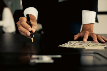 Man counting money in hand and pen.