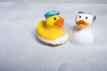 Two rubber ducks on a light background in soapy foam.