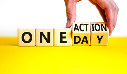 One day and action symbol. Concept words One day and One action on wooden cubes. Businessman hand. Beautiful yellow table white background. Business One day and action concept. Copy space.