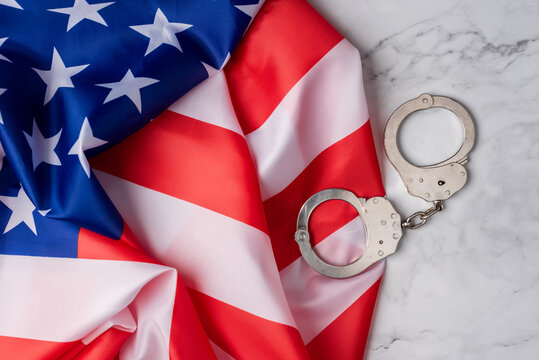 Wallpaper with the flag of the united states next to handcuffs on a white marble base. American judicial system