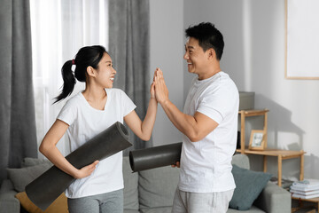 Positive asian man and woman with yoga mats
