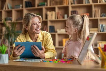 Preschool education concept. Clever girl learning alphabet, exercising with tutor at classroom