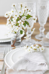 Rustic zero waste wedding decor with natural elements. Wooden table, candles, linen napkins, branches with green leaves. Eco-friendly decoration for the special dinner. Romantic and cozy place