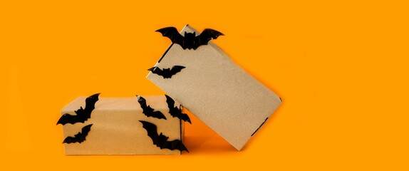 Banner, on an orange background festive boxes for Halloween decorated with black decorative bats.  The concept of holiday sales, discounts, gift shopping.  Space for copy text.