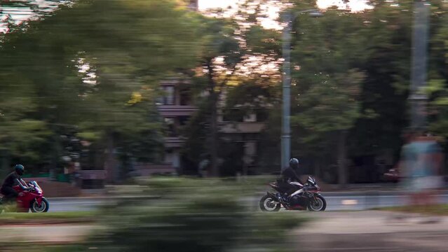 Rolling shot follow crane of two men bikers riding motorbikes in the city street at sunset. Motorcyclists racing on motorcycles on the street