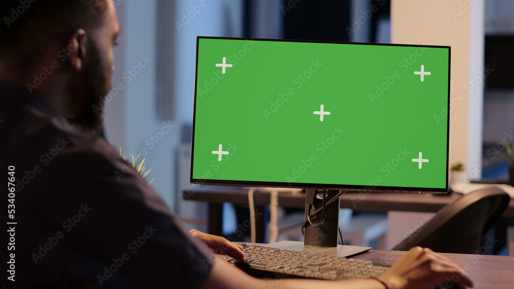 Poster african american man looking at computer with greenscreen, analyzing isolated display on desktop mon