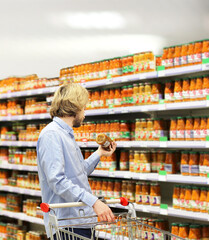 Young man shopping in supermarket, reading product information