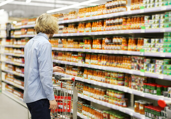 Young man shopping in supermarket, reading product information